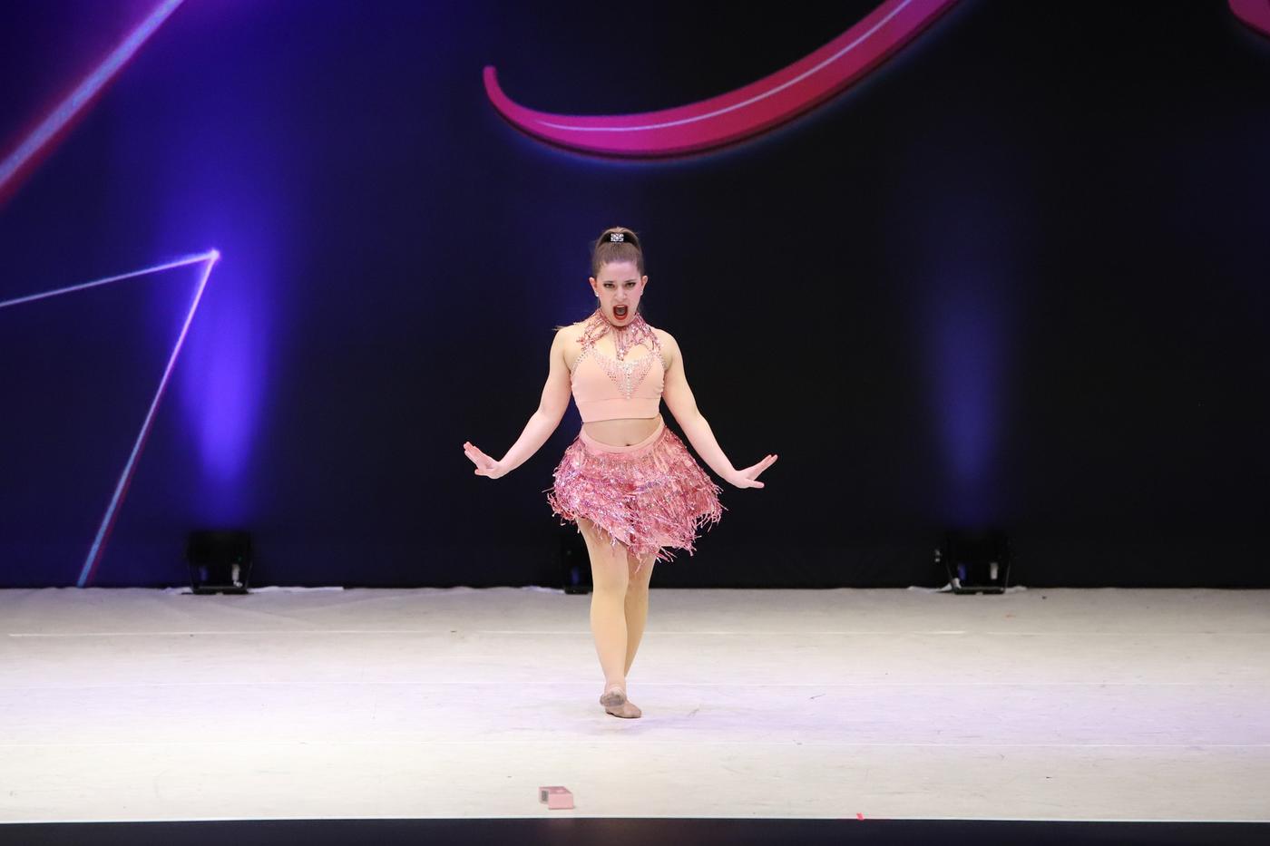 Ariella Sinclair performing a competition solo in pink fringe costume