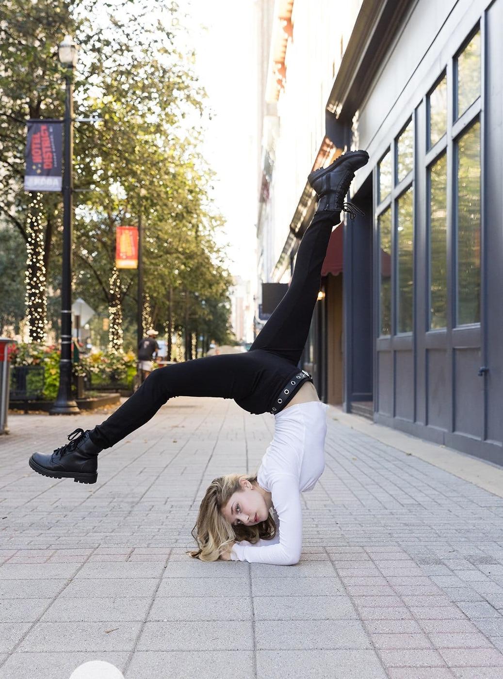 Ariella Sinclair in a one-armed inverted dance pose on a city sidewalk