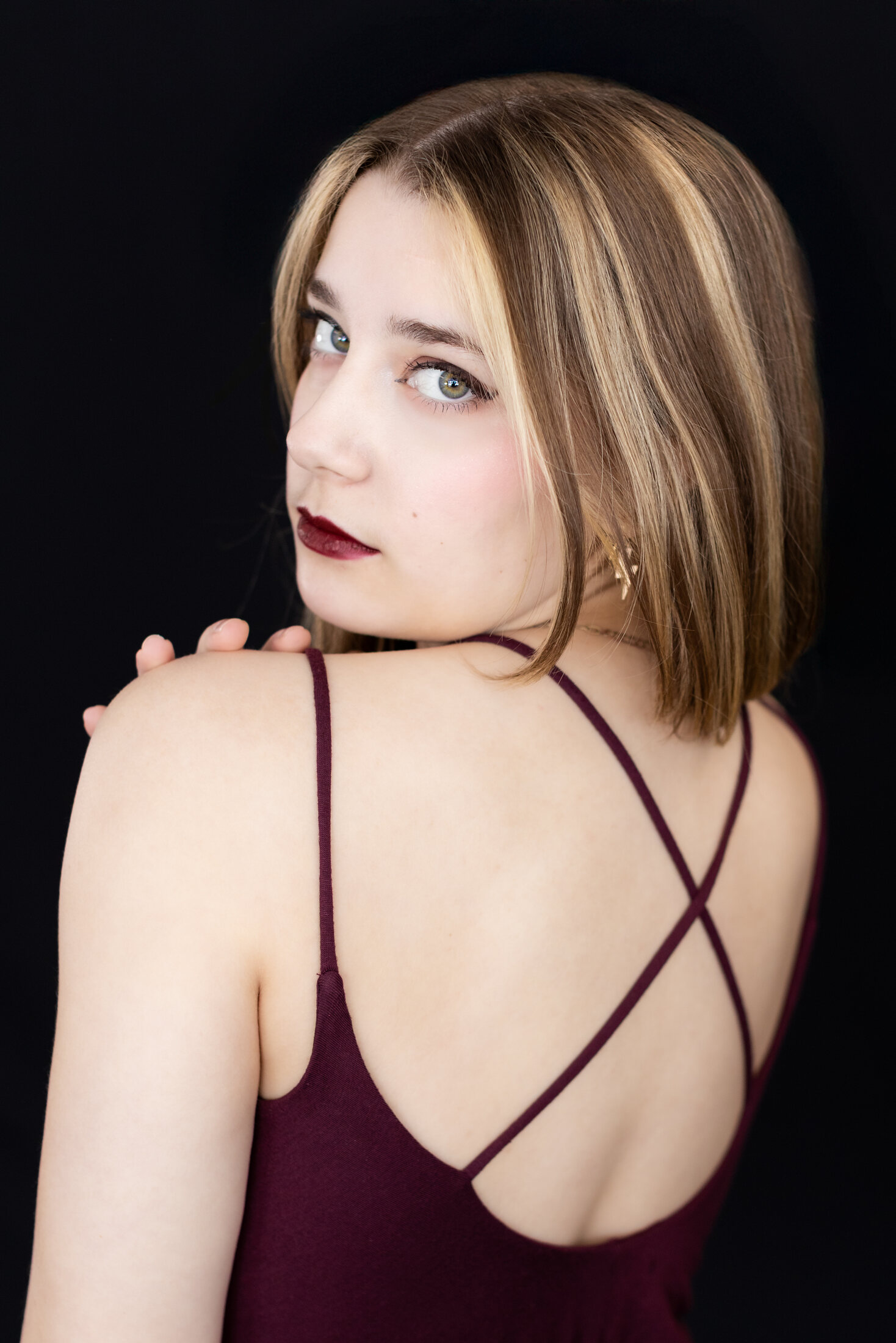 Ariella Sinclair editorial portrait, looking over her shoulder in a burgundy top