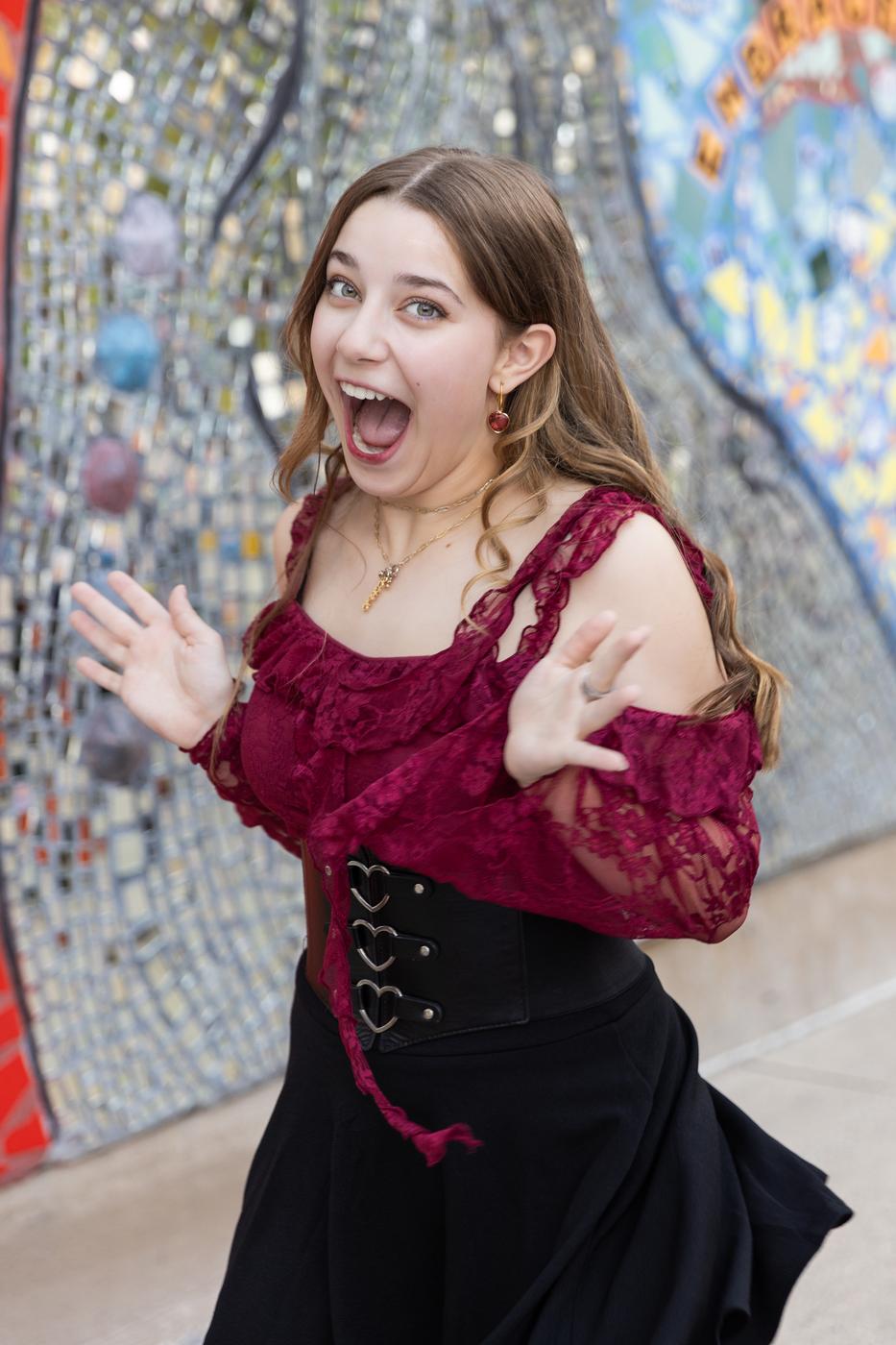 Ariella Sinclair laughing in close-up, burgundy lace top