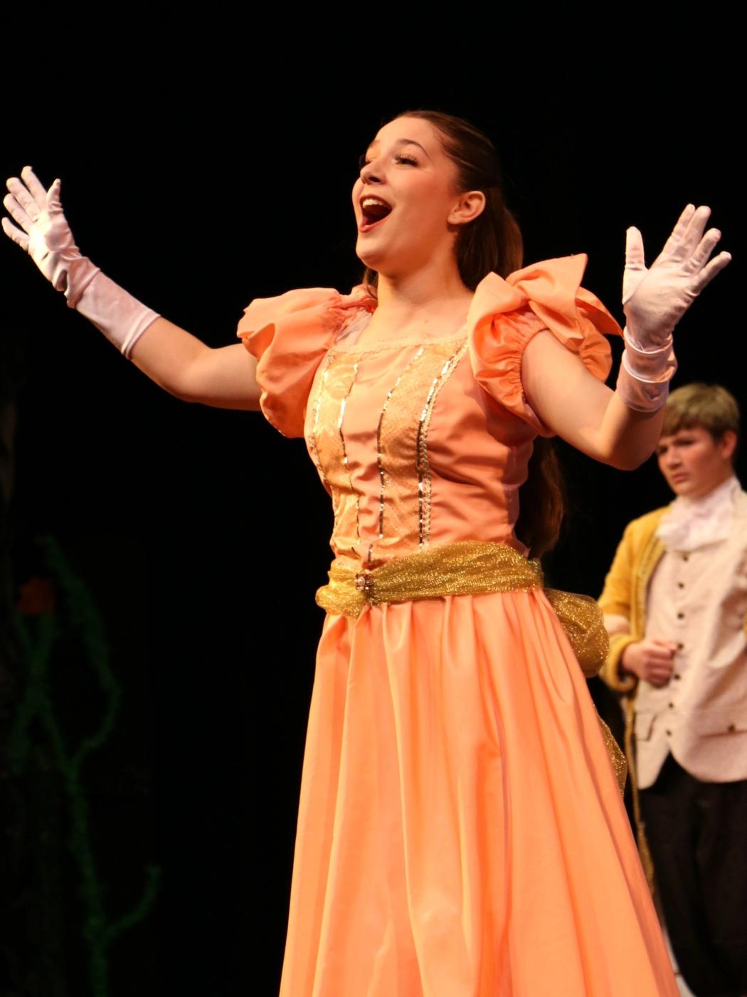 Ariella Sinclair as a princess in The Little Mermaid play, in a peach gown with arms raised in song
