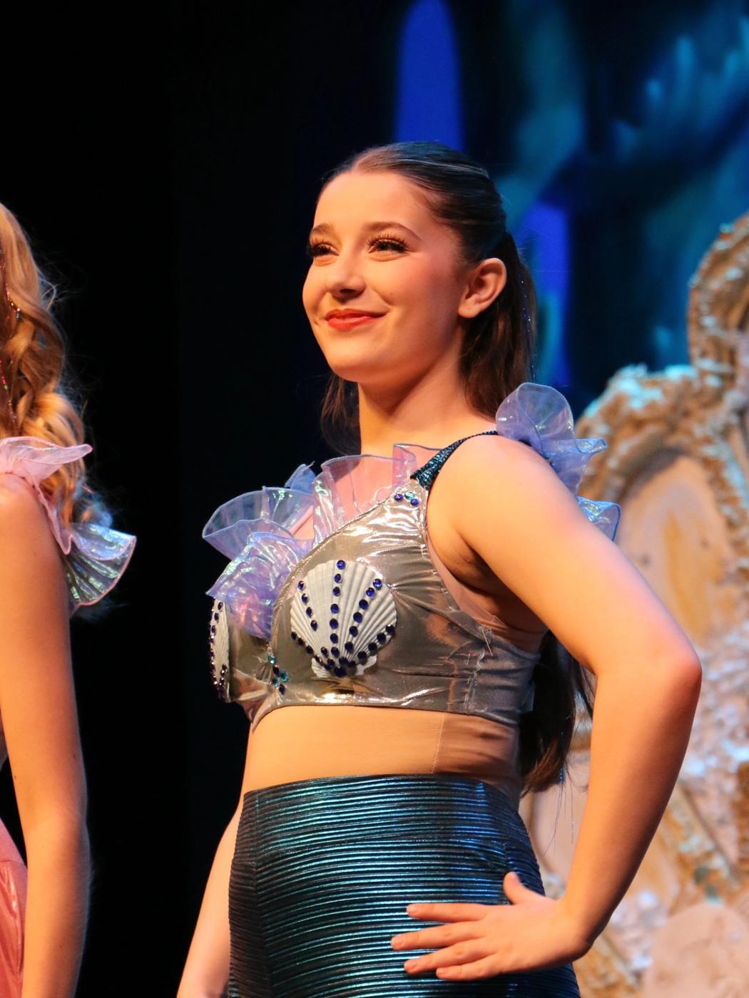 Ariella Sinclair as one of Ariel's mermaid sisters in silver shell costume