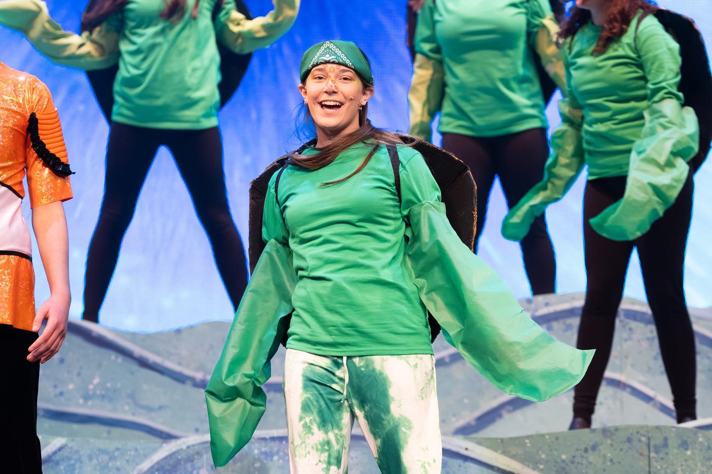Ariella Sinclair as Crush in Finding Nemo, center stage in green costume